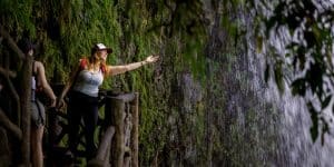 Woman reaching into a waterfall.